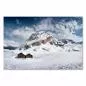 Preview: Atemberaubendes Alpenpanorama mit einsamer Berghütte, Schnee und tiefblauen Wolken schaffen Winteratmosphäre.